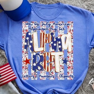 May include: A light blue t-shirt with a patriotic design. The design features the words "ALMOST BUT" in red, white, and blue, with stars and stripes. The shirt also includes the text "4th Of July America Alphabet Png Set".