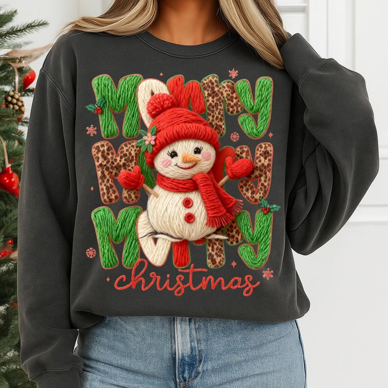 May include: Dark gray sweatshirt with a festive Christmas design. The design features a snowman wearing a red hat, scarf, and mittens, surrounded by the words "Merry Christmas" in green and leopard print letters.