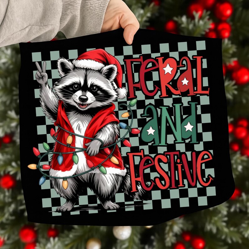 May include: Black square with a raccoon wearing a Santa hat and red vest, holding up a peace sign. The text "Feral and Festive" is in red and green, with a string of Christmas lights.