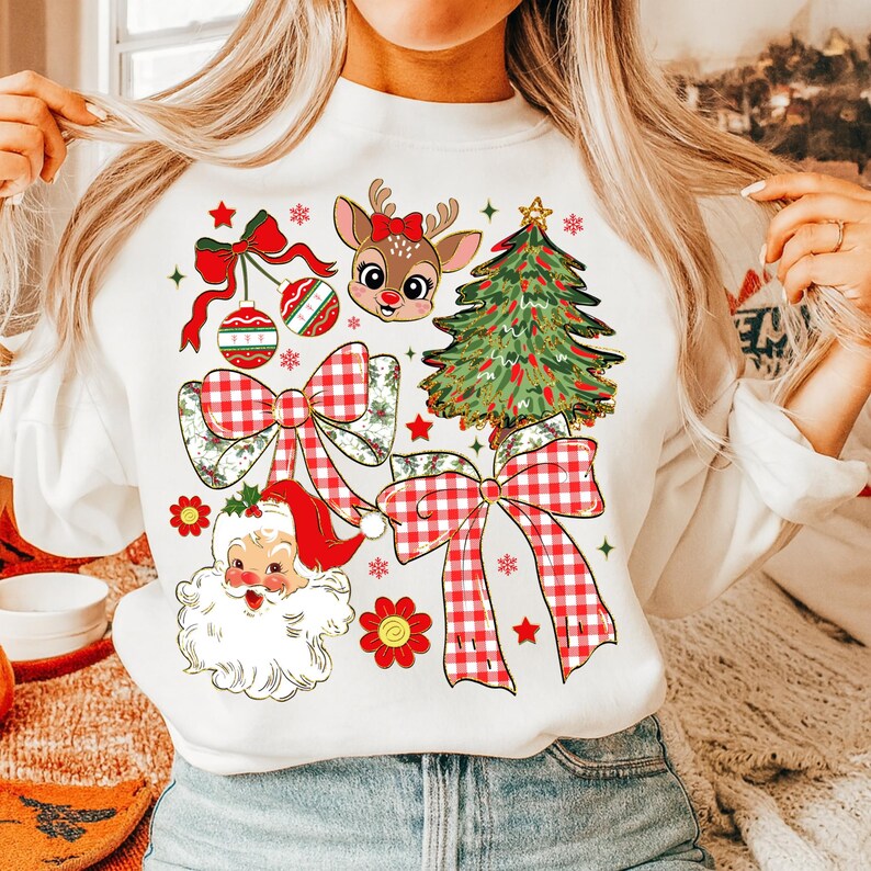 May include: White sweatshirt with festive Christmas graphics. The design includes a reindeer with a red bow, a Christmas tree, Santa Claus, red bows, ornaments, and snowflakes. The graphics are in red, green, and white.