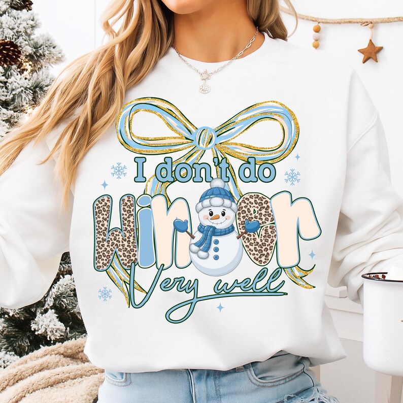 May include: White sweatshirt with a winter-themed graphic. The design includes a snowman wearing a blue hat and scarf, and the text "I don't do winter very well." The word "winter" has a leopard print pattern.