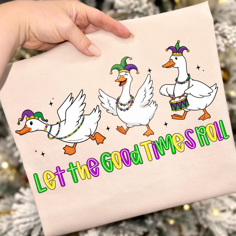 May include: A light pink square featuring three cartoon geese in Mardi Gras attire. The geese are white with orange feet and beaks, wearing jester hats and beaded necklaces. One goose plays a drum. The text "Let the Good Times Roll" is below the geese.