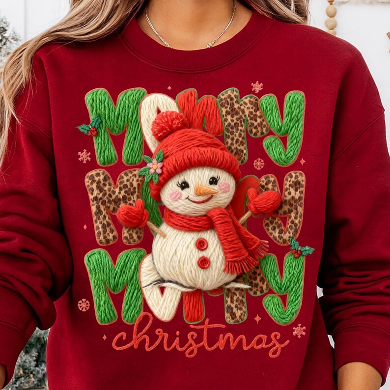 May include: A red sweatshirt with a festive Christmas design. The design features the words "Merry Christmas" with a snowman wearing a red hat, scarf, and mittens. The letters are green and leopard print.