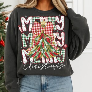 May include: Dark gray sweatshirt with a festive Christmas design. The graphic features the words "MERRY MERRY MERRY Christmas" in a mix of fonts and patterns, including a Christmas tree and bow. Candy cane and snowflake accents complete the holiday theme.