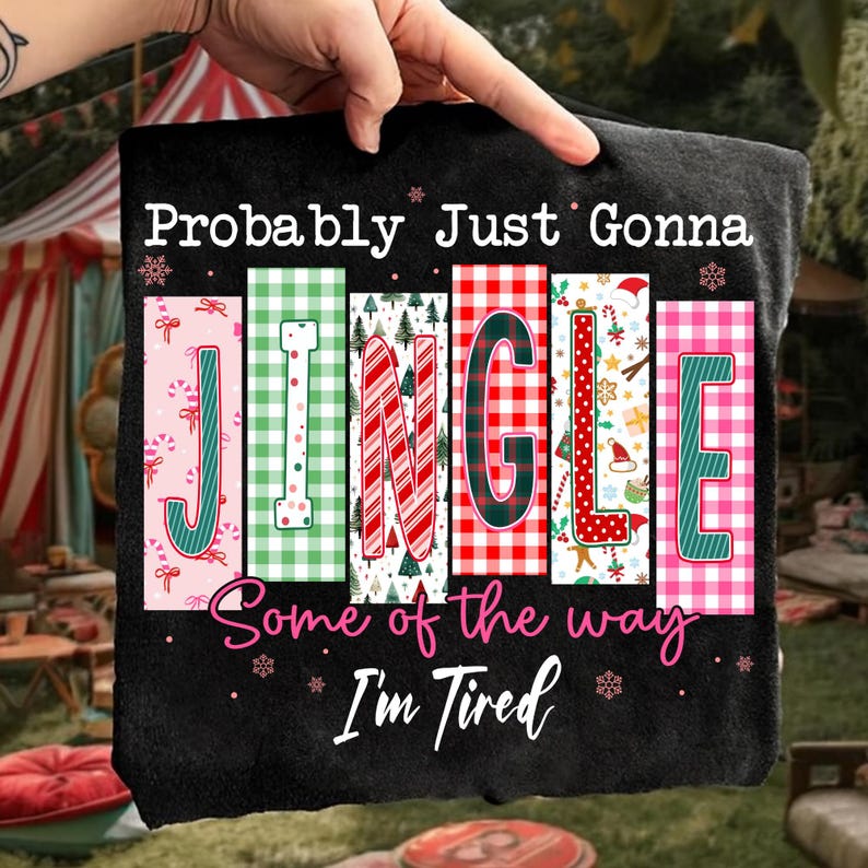May include: Black t-shirt with the text "Probably Just Gonna JINGLE Some of the way I'm Tired." The word "JINGLE" is in colorful, festive blocks with candy canes, plaid, and Christmas tree designs.
