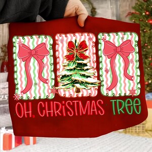 May include: A red Christmas-themed pillow with three decorative panels. Each panel features a pink bow or a green Christmas tree with a red bow. The text "OH. CHRISTMAS TREE" is in green and red script.