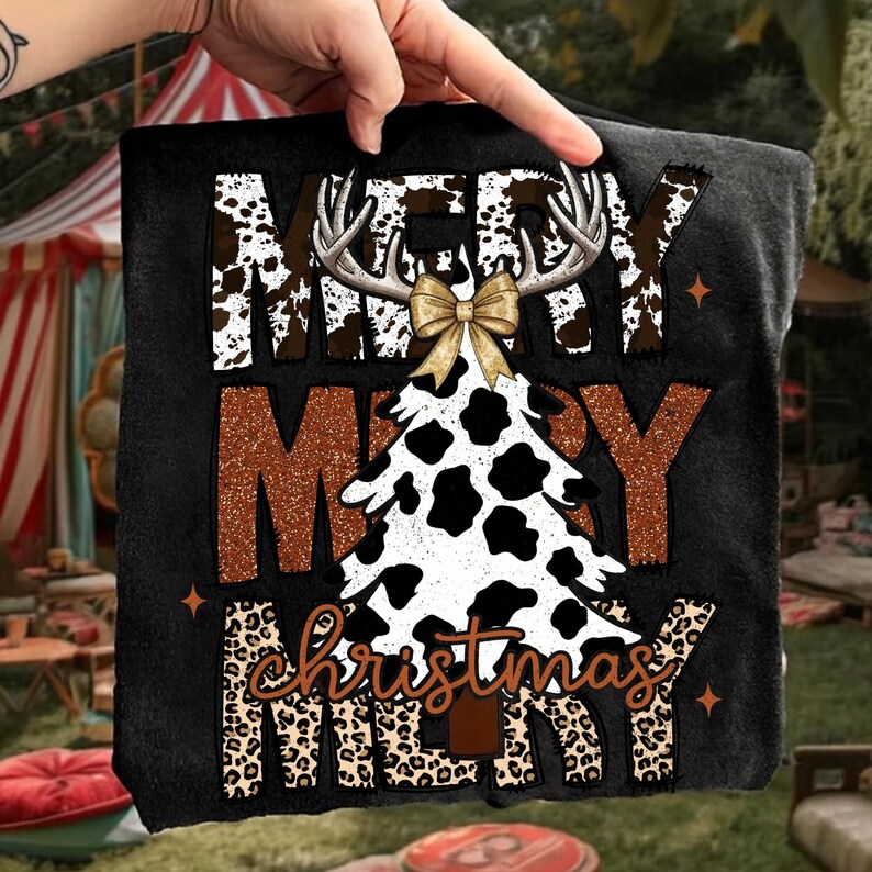 May include: Black t-shirt with a Christmas design. The design includes the words "MERRY CHRISTMAS" in a mix of fonts and patterns, including cow print, leopard print, and a Christmas tree shape. A gold bow and antlers are also part of the design.