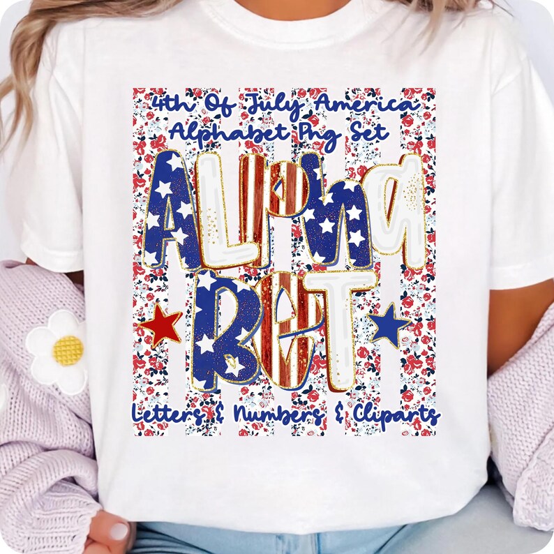 May include: White t-shirt with a 4th of July design. The design features the word "ALPHABET" in a bold font with red, white, and blue stars and stripes. The shirt also includes the text "Letters & Numbers & Cliparts" against a floral background.