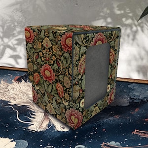 May include: A square deck box featuring a dark green background with a dense floral pattern of red and orange peonies and intricate gold foliage. The box has a rectangular cutout on the front panel and a smooth, matte-textured finish throughout.