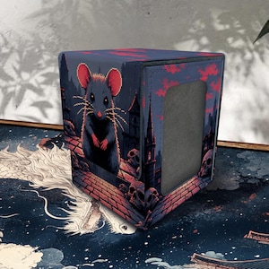 May include: A square deck box featuring a dark, gothic-inspired illustration of a grey mouse standing on a brick rooftop with skulls, a tall spire, and red clouds. The box has a solid grey rectangular panel on its side and a textured surface finish.