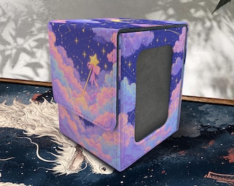 Puede incluir: Una caja para barajas rectangular con un estampado de cielo nocturno en tonos morados y azules, nubes rosas, estrellas amarillas y un gráfico de varita dorada. Incluye una ventana rectangular gris oscuro y un cierre de solapa magnético.