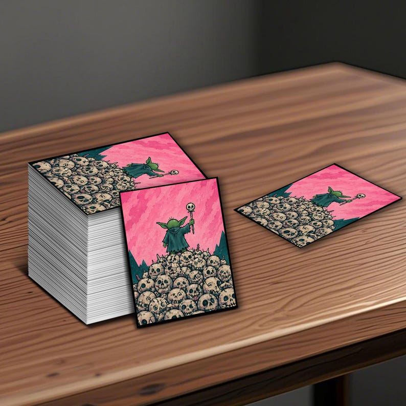 Puede incluir: Tarjetas rectangulares con un personaje de dibujos animados con una t&uacute;nica verde sosteniendo un bast&oacute;n, de pie sobre una pila de calaveras. El fondo es rosa con un borde verde oscuro. Las tarjetas est&aacute;n sobre una superficie de madera.
