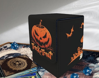May include: Black storage box with a Halloween theme. The box features an orange jack-o'-lantern and the words "Trick or Treat." Bats and a ghost are also visible. The box is designed to hold cards and dice.