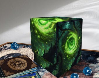 May include: A cube-shaped card deck box with a green and black fantasy art design featuring swirling green energy and dark silhouettes. The box is surrounded by blue dice and a deck of cards.
