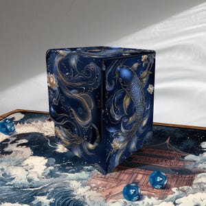 Può includere: Una scatola blu navy con un design a koi. La scatola presenta dettagli dorati e bianchi, con un'illustrazione dettagliata di pesci koi, fiori e motivi a vortice. La scatola è progettata per riporre oggetti.
