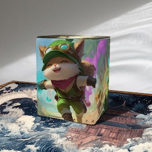 Puede incluir: Una caja de almacenamiento cúbica con un personaje de dibujos animados con un atuendo verde, sombrero y mochila. El personaje está sonriendo y corriendo. La caja tiene un diseño ilustrado colorido con un tema de fantasía.