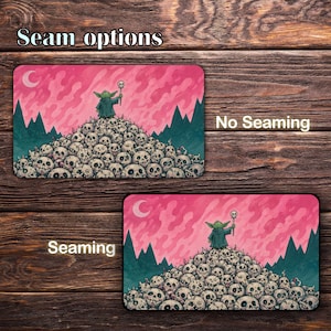 May include: Two rectangular mouse pads with rounded corners. The top pad is labeled "No Seaming" and the bottom pad is labeled "Seaming". Each pad features a cartoon character on a pile of skulls, with a pink sky and green mountains.
