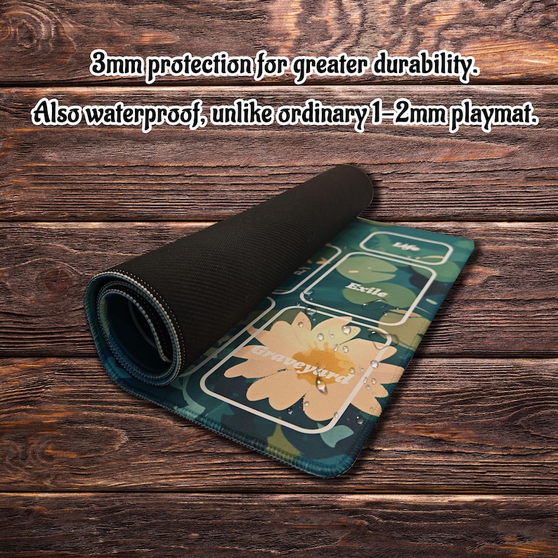May include: A rectangular playmat with a black underside and a top surface featuring a green lily pad design with a yellow flower and the text Graveyard, Life, and Exile. The text states 3mm protection for greater durability. Also waterproof, unlike ordinary 1-2mm playmat.