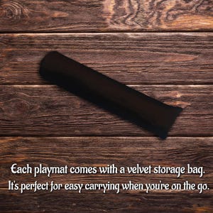 May include: A long, cylindrical black velvet storage bag with a soft, matte texture. The bag is positioned diagonally across the frame. The text on the image reads: Each playmat comes with a velvet storage bag. It's perfect for easy carrying when you're on the go.