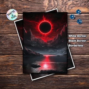 Könnte beinhalten: Zwei Kunstdrucke mit einer dramatischen Landschaft mit einem rot leuchtenden Himmelskörper. Die Drucke sind übereinander angeordnet, einer mit weißem Rand, der andere mit schwarzem Rand. Der Text "Matte & Foil" befindet sich auf einem holografischen Aufkleber. Würfel sind sichtbar.
