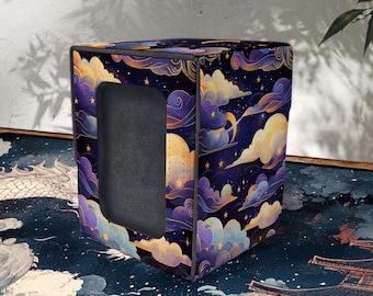 Puede incluir: Una caja de almacenamiento cúbica con un diseño celestial que presenta nubes, estrellas y lunas en tonos morados, amarillos y azules. La caja tiene una abertura rectangular en un lado.