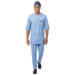 May include: A light blue traditional African outfit, consisting of a short-sleeved tunic and matching trousers. The tunic has black trim on the pockets and neckline. A patterned cap and black shoes complete the ensemble.