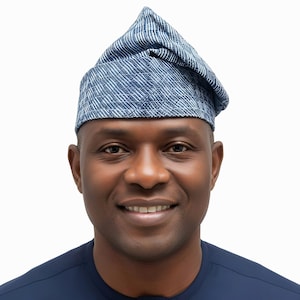 May include: A blue and white patterned hat with a pointed crown. The hat is made of a textured fabric and is worn on the head. The person in the image is wearing a dark blue shirt.