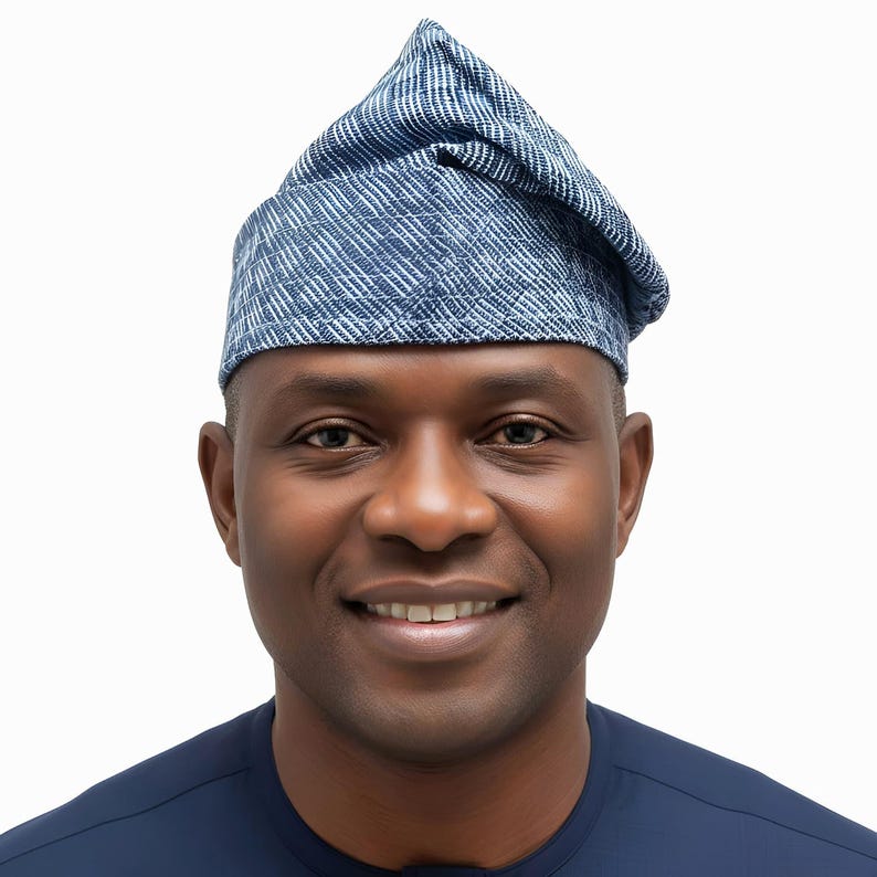 May include: A blue and white patterned hat with a pointed crown. The hat is made of a textured fabric and is worn on the head. The person in the image is wearing a dark blue shirt.