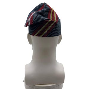 May include: A striped hat with a folded brim, featuring red, white, and yellow stripes on a dark blue background. The hat is displayed on a white mannequin head.