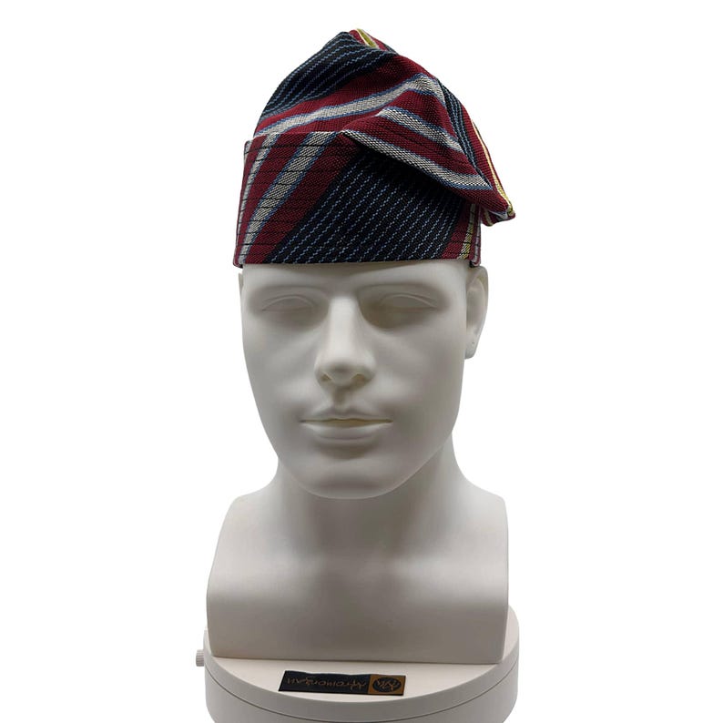 May include: A patterned hat with red, white, and navy blue stripes, displayed on a white mannequin head. The hat has a folded brim and a pointed crown. The fabric appears to be woven.