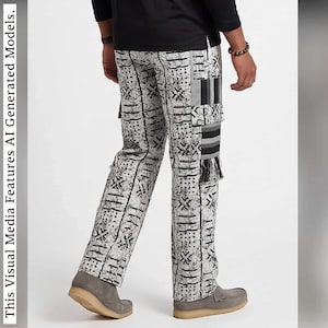 May include: Full-length trousers featuring a light gray base with a black abstract geometric and splatter print. The pants include a side cargo pocket with a vertical striped panel and a frayed fringe detail along the lower leg section.