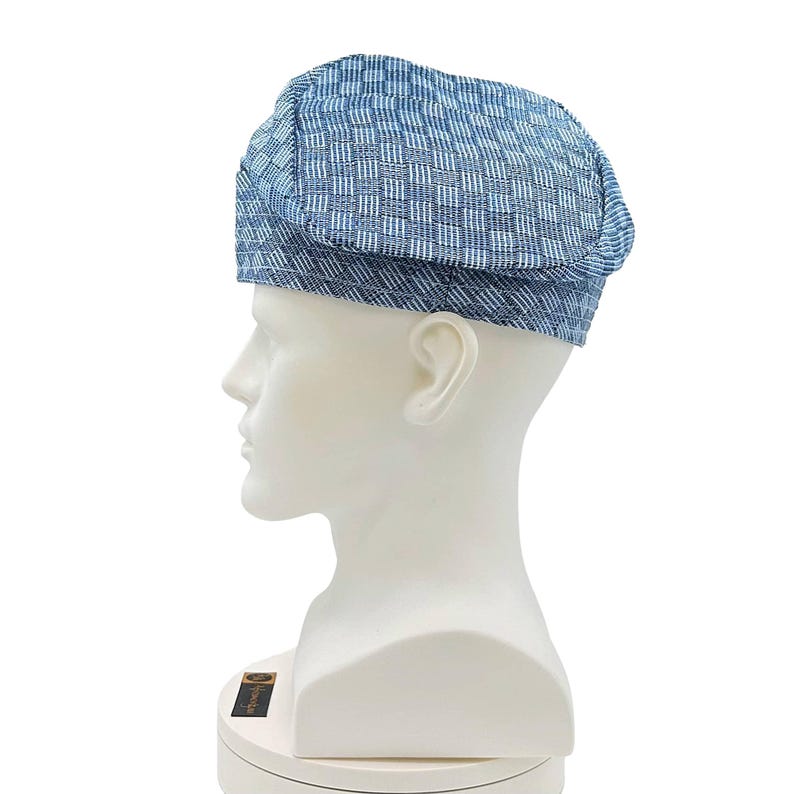 May include: A blue and white patterned hat, displayed on a white mannequin head. The hat has a woven texture and a classic, rounded shape. The color scheme is a mix of light and dark blues with white accents, creating a textured appearance.