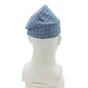 May include: A blue and white patterned hat with a triangular crown and a small brim. The hat is made of a woven fabric and is displayed on a white mannequin head. The hat's design features a mix of blue and white horizontal and vertical lines.
