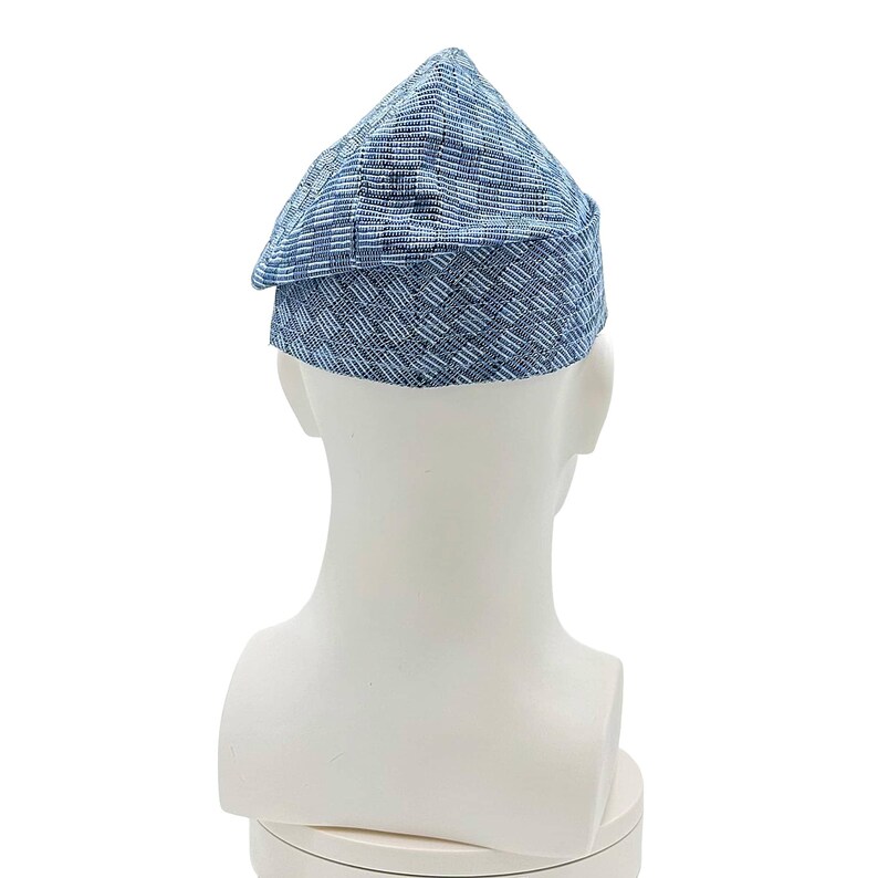 May include: A blue and white patterned hat with a triangular crown and a small brim. The hat is made of a woven fabric and is displayed on a white mannequin head. The hat's design features a mix of blue and white horizontal and vertical lines.
