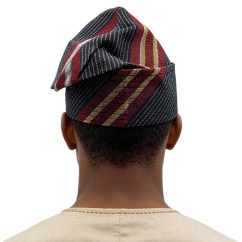 May include: A traditional African hat, seen from behind. The hat has a striped pattern in black, red, white, and yellow. The person is wearing a beige shirt. The hat is a cultural garment.