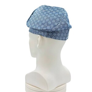 May include: A blue and white patterned newsboy cap. The cap is made of a woven fabric and is displayed on a white mannequin head. The cap has a classic, rounded shape with a small brim.