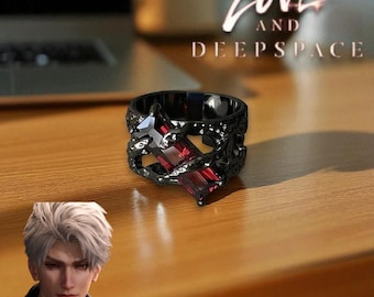 May include: A black ring with a geometric design, featuring a large, rectangular red gemstone. The ring is set on a wooden surface, with the words "Love and Deepspace" visible in the background.