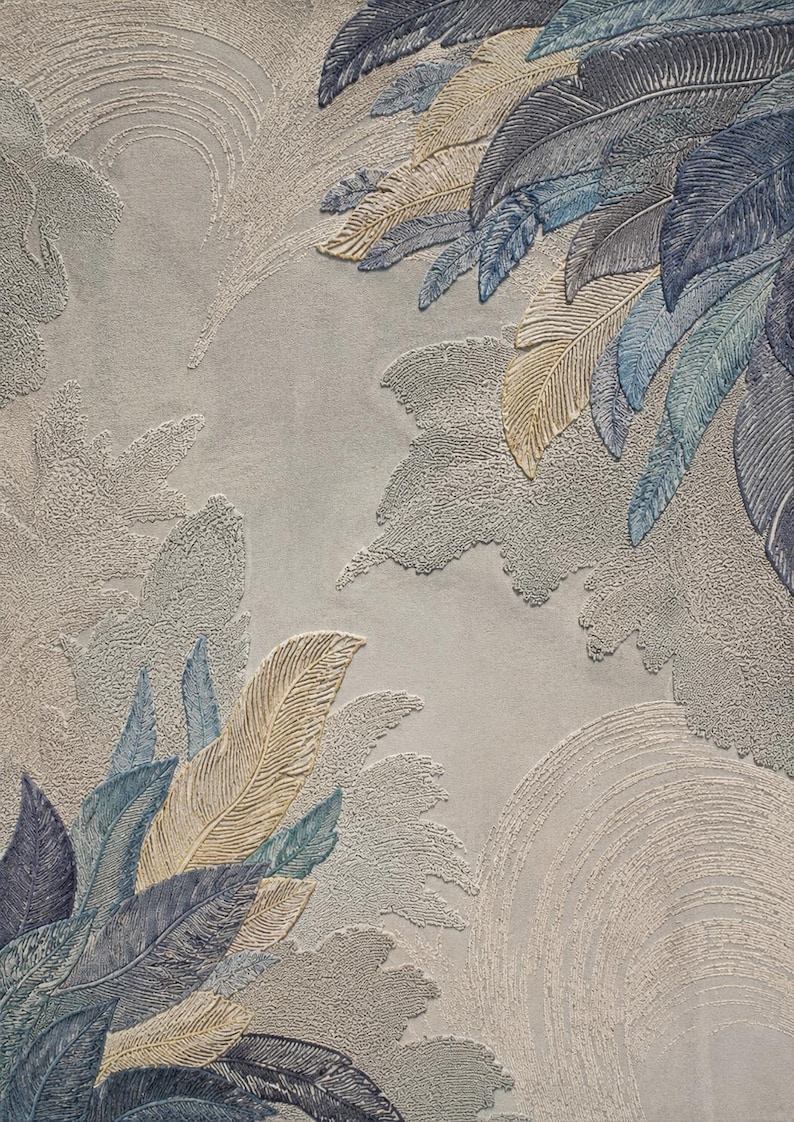 Op de afbeelding: Getextureerd kunstwerk met gestileerde veren in tinten blauw, beige en grijs. De veren zijn gerangschikt in een gelaagd patroon tegen een lichtgrijze achtergrond, waardoor een gevoel van diepte en beweging ontstaat. Het kunstwerk heeft een zachte, bijna wolkachtige uitstraling.