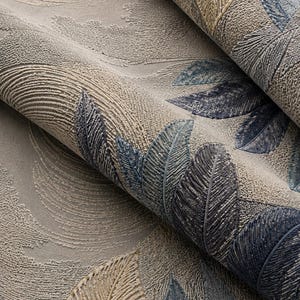 Op de afbeelding: Close-up van getextureerd behang met een herhalend veermotief. De veren zijn in tinten blauw, beige en grijs, waardoor een gelaagd effect ontstaat. De achtergrond heeft een subtiel, wervelend patroon. Geschikt voor interieurdecoratie.