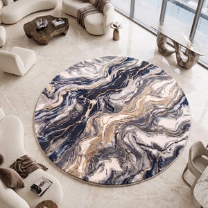 May include: A round area rug with a marbled design in shades of blue, gray, and beige. The rug is placed on a light-colored marble floor, surrounded by modern furniture. The rug's pattern resembles flowing water or stone.