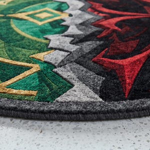 Side view close-up of hand tufted wool and Tencel round rug showing thick edge binding and dense pile texture in green and red abstract design