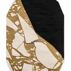 May include: An octagonal rug featuring a split design with a solid black section and a textured gold base. The gold portion is overlaid with irregular, raised white shapes that resemble scattered stone fragments or abstract geometric shards.