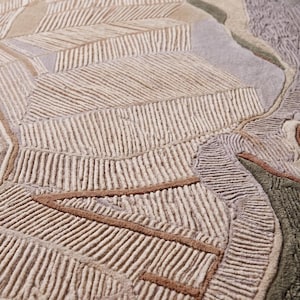 May include: A tufted area rug featuring an abstract landscape design with textured, raised lines in shades of beige, cream, sage green, lavender, and terracotta. The surface displays a mix of high-pile tufted sections and flat-woven areas.