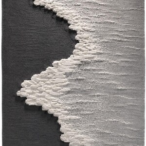 Op de afbeelding: Getextureerde wandkunst met een gestileerde afbeelding van een golf. Het kunstwerk contrasteert een donkergrijs gebied met een witte, schuimige golfkam langs de rand. Het stuk heeft een tastbare, driedimensionale kwaliteit, wat duidt op een reli&euml;fsculptuur.