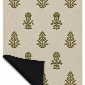 May include: A rectangular area rug featuring a light beige background with a repeating pattern of olive green botanical motifs. The bottom left corner of the rug is folded over to reveal a solid black underside, showing the contrast in color.