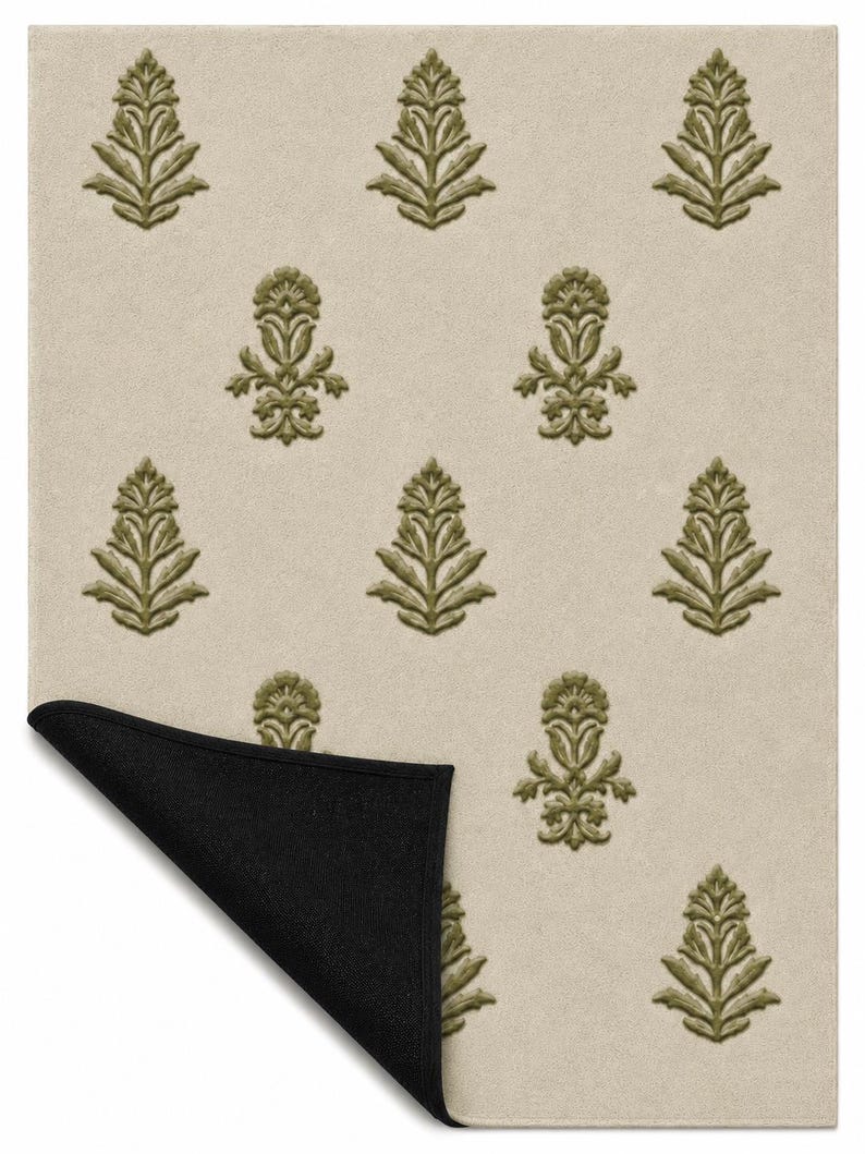 May include: A rectangular area rug featuring a light beige background with a repeating pattern of olive green botanical motifs. The bottom left corner of the rug is folded over to reveal a solid black underside, showing the contrast in color.