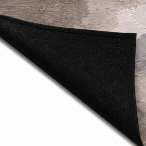 May include: A rectangular floor mat with a folded corner revealing a black, textured, non-slip underside. The top surface features a marbled pattern in shades of beige, gray, and white with a smooth finish and a solid black fabric border.