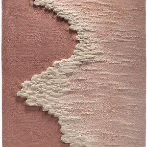 Op de afbeelding: Een getextureerd, abstract tapijt in roze en witte tinten. Het ontwerp heeft een golfachtig patroon in wit, dat contrasteert met de roze achtergrond. Het oppervlak van het tapijt lijkt een verhoogde, driedimensionale textuur te hebben.