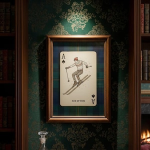 May include: Framed playing card art featuring the Ace of Spades with a skier illustration. The card has a plaid background and is set in a wooden frame. The text "ACE OF SKIS" is at the bottom of the card.