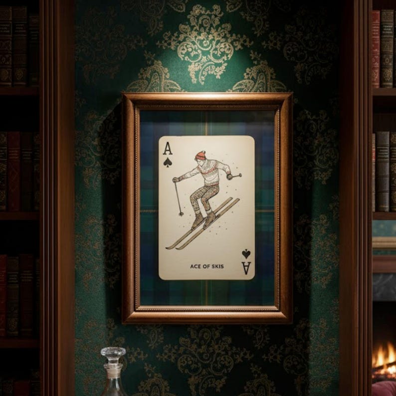 May include: Framed playing card art featuring the Ace of Spades with a skier illustration. The card has a plaid background and is set in a wooden frame. The text "ACE OF SKIS" is at the bottom of the card.